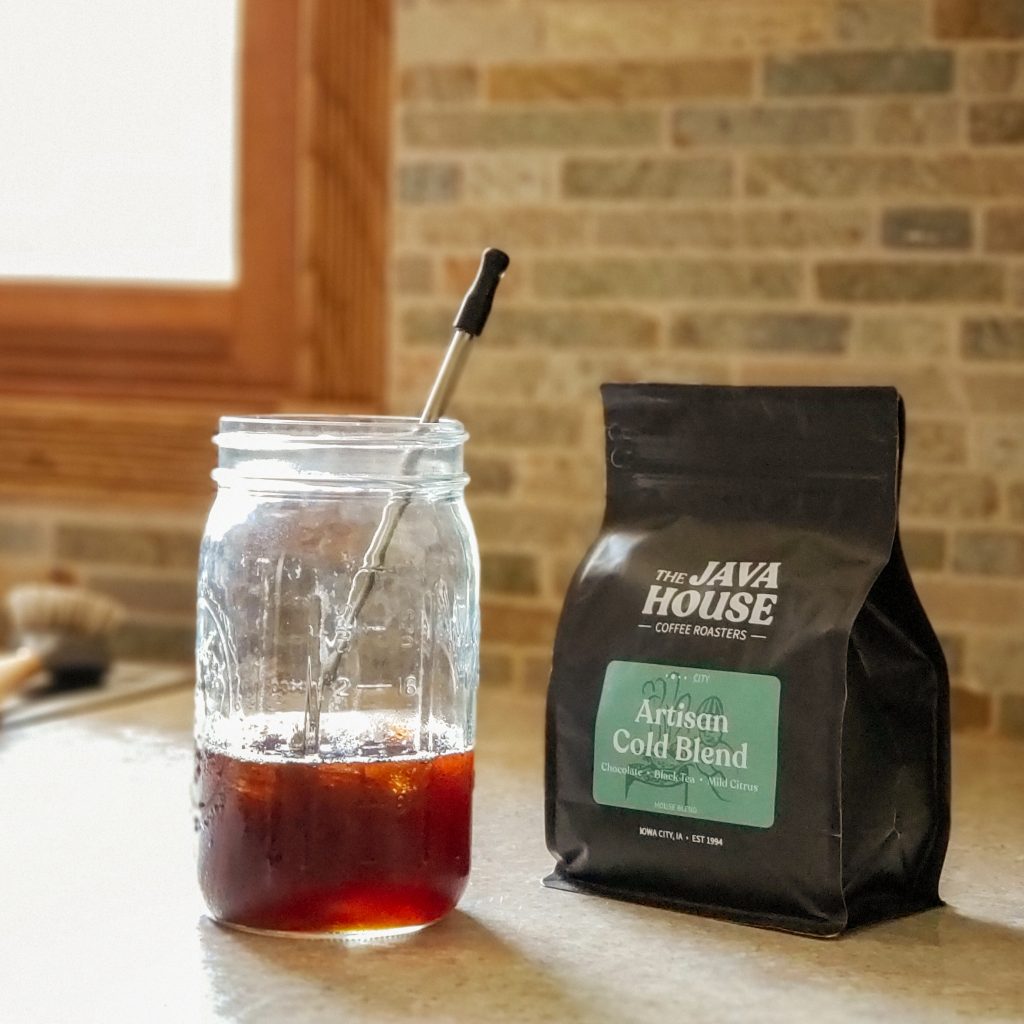 a bag of artisan cold blend coffee sitting on the kitchen counter next to a mason jar of iced coffee