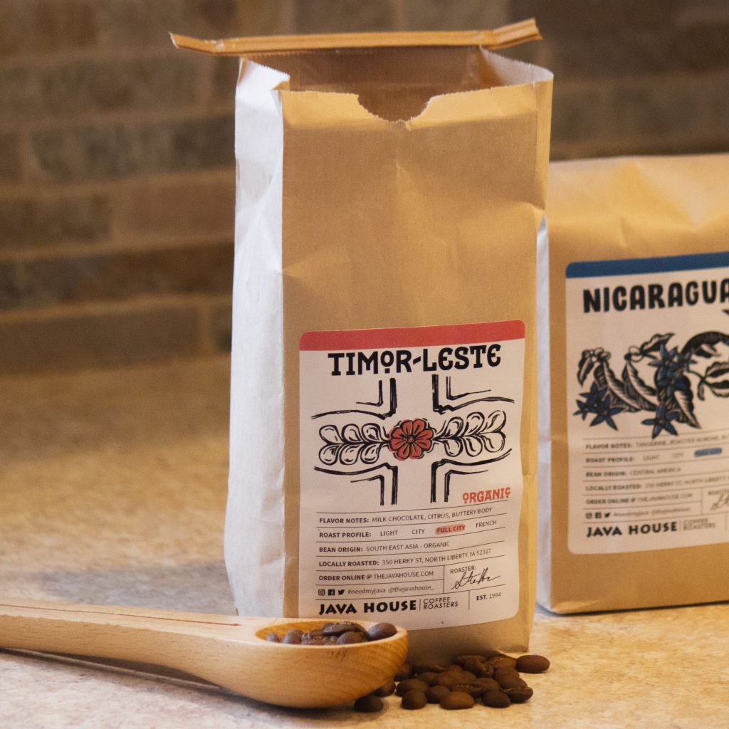 a bag of timor-leste in a brown kraft bag, with coffee beans in the foreground